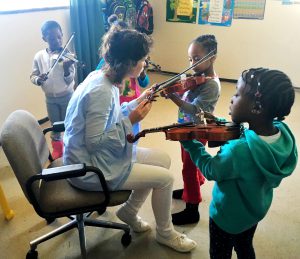 Teacher assisting children with violin